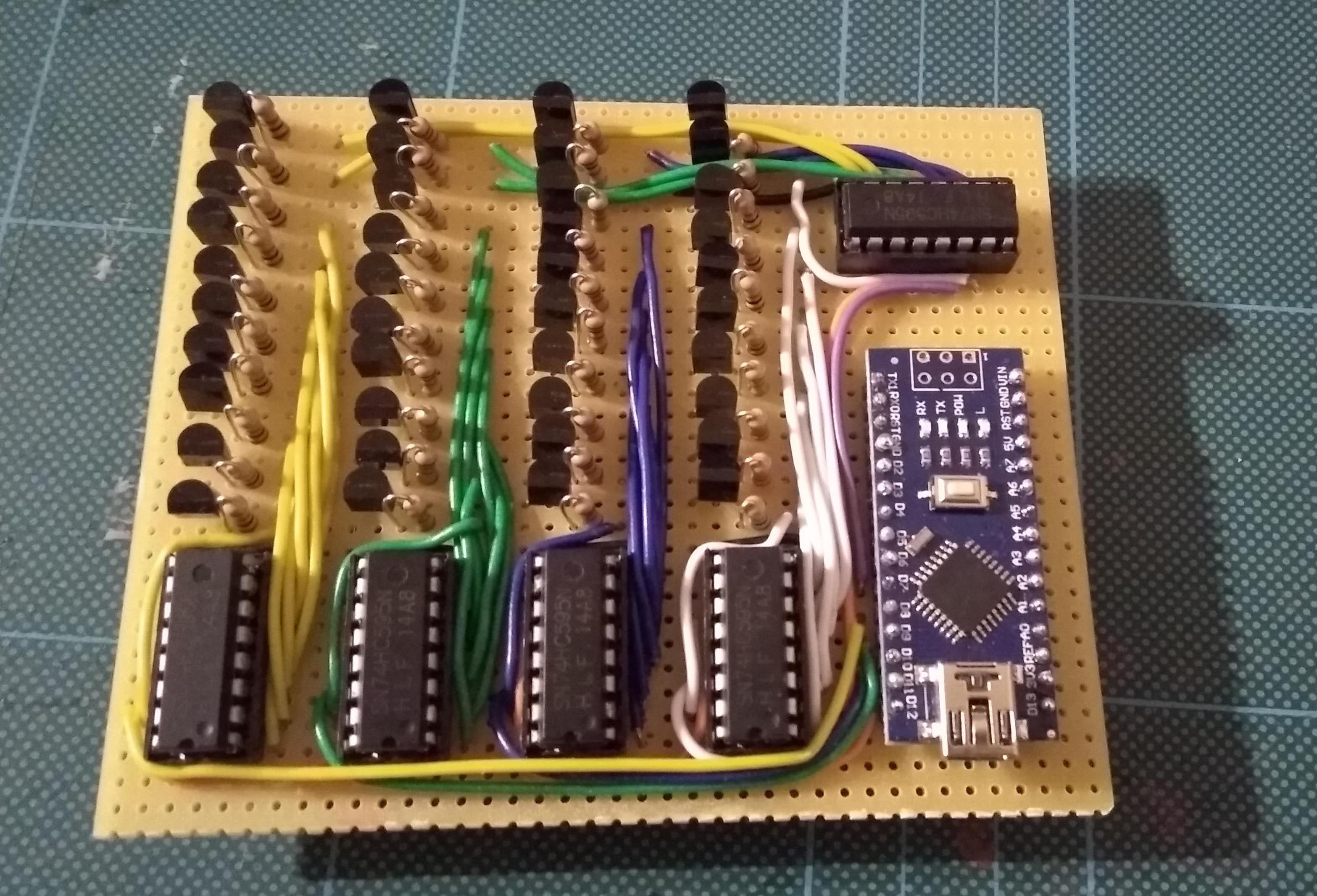 Stripboard circuit with four 74HC595 shift registers, rows of tactile buttons and an Arduino Nano, built on a cutting mat